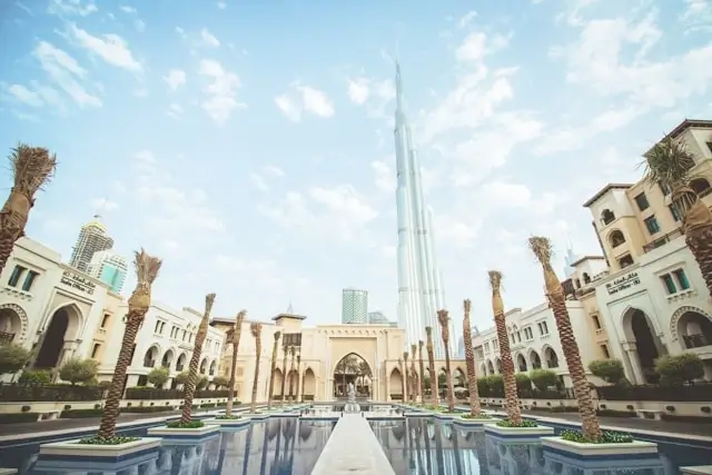 Burj Khalifa towering over luxury hotel courtyard with reflecting pools and palm trees in Dubai UAE during summer off-season