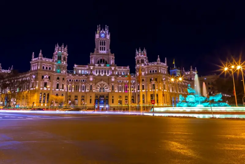 Cibeles Palace illuminated at night with the iconic fountain glowing in turquoise light in Madrid, Spain