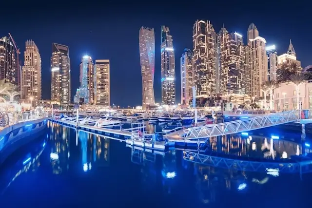 Luxury high-rise hotels near Dubai Mall with illuminated blue fountain display and Downtown Dubai skyline at night