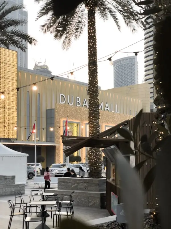 Dubai Mall main entrance with golden facade and palm trees, surrounded by nearby hotels in Downtown Dubai