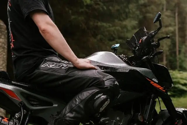 Person's hand resting on fuel tank of black KTM motorcycle in outdoor setting