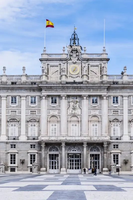 Royal Palace of Madrid facade with Spanish flag flying above the ornate baroque architecture and central courtyard