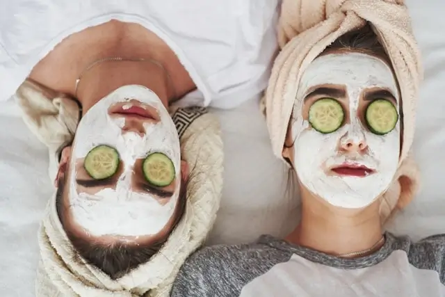 Friends relaxing with facial treatments at bachelorette party sleepover spa night