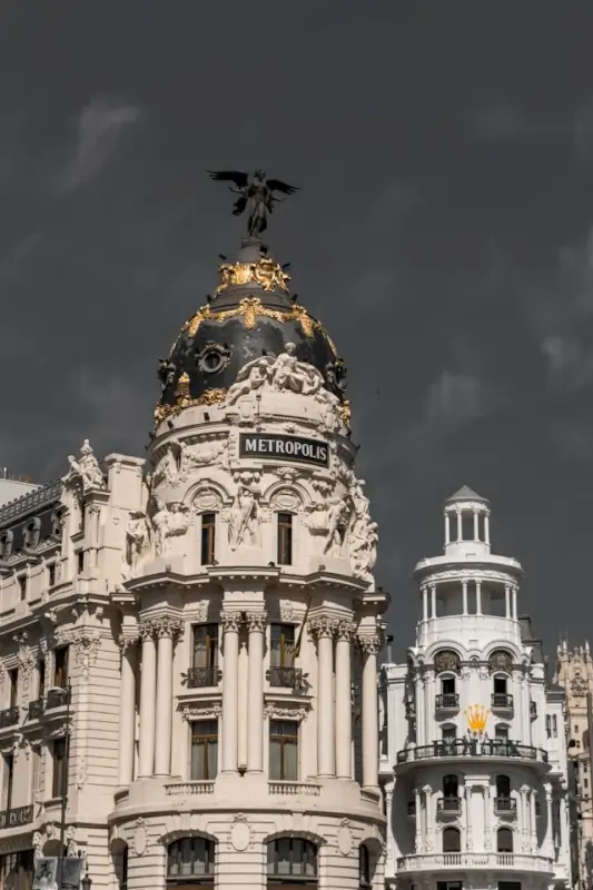 Metropolis Building dome with winged victory statue and golden details against dramatic sky in Madrid's Gran Via