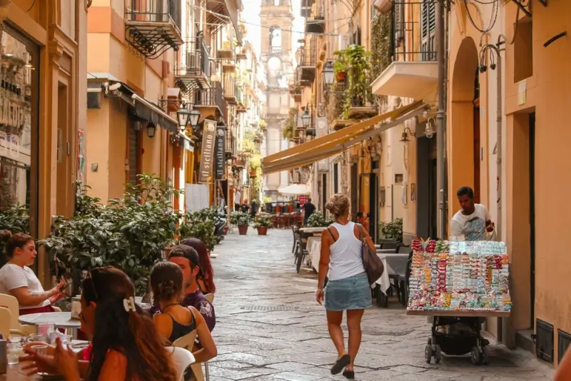 Charming narrow street with cafes and local vendors in historic Sicilian city center