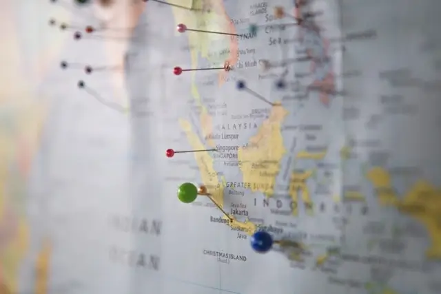 Close-up of a world map with colorful pushpins marking travel destinations across Southeast Asia, including Malaysia, Singapore, and Indonesia