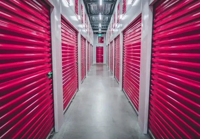 Interior corridor of a climate-controlled storage facility lined with vibrant pink roll-up storage unit doors on both sides, featuring white framing and polished concrete floors