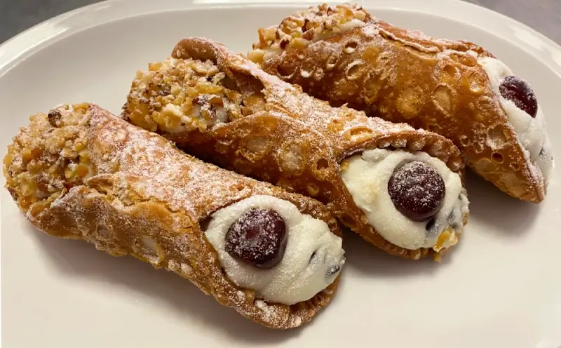 Traditional Sicilian cannoli filled with sweet ricotta and chocolate chips on white plate