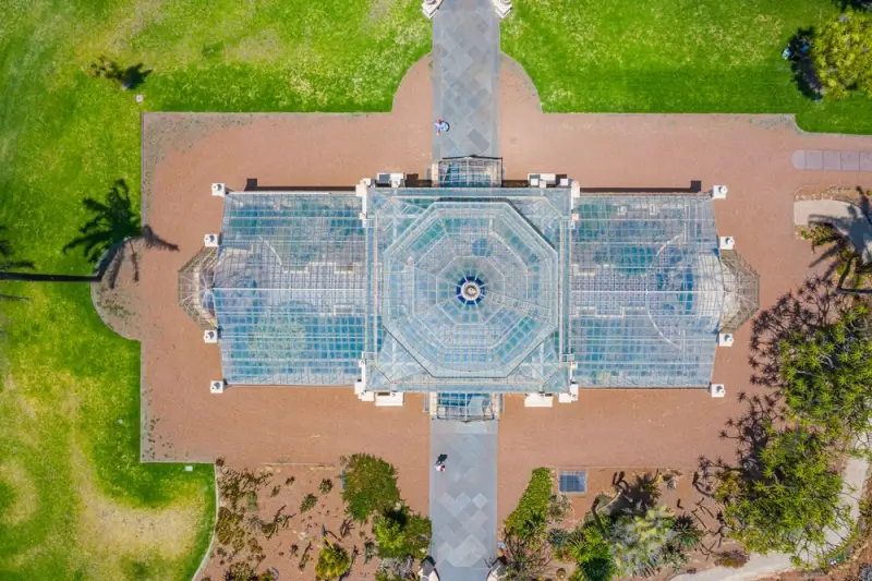 Aerial view of historic Palm House conservatory at Adelaide Botanic Garden surrounded by landscaped gardens in South Australia