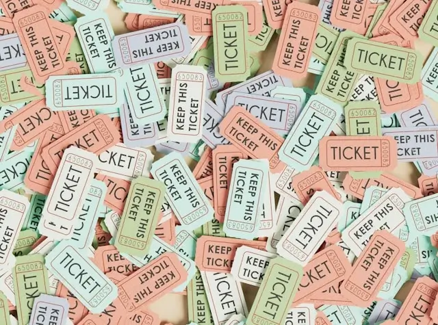 Assortment of colorful ticket stubs in pink, blue, and green with 'TICKET' and 'KEEP THIS TICKET' text, scattered as travel keepsakes and mementos