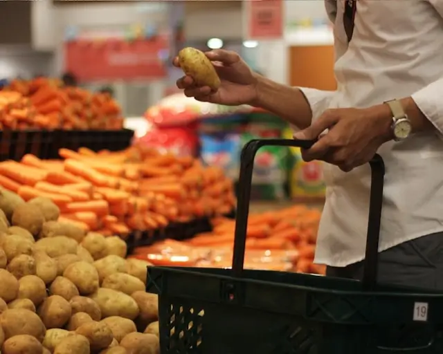 Person selecting fresh potatoes at colorful produce market, combining travel and cooking inspiration by sourcing ingredients for home recipes