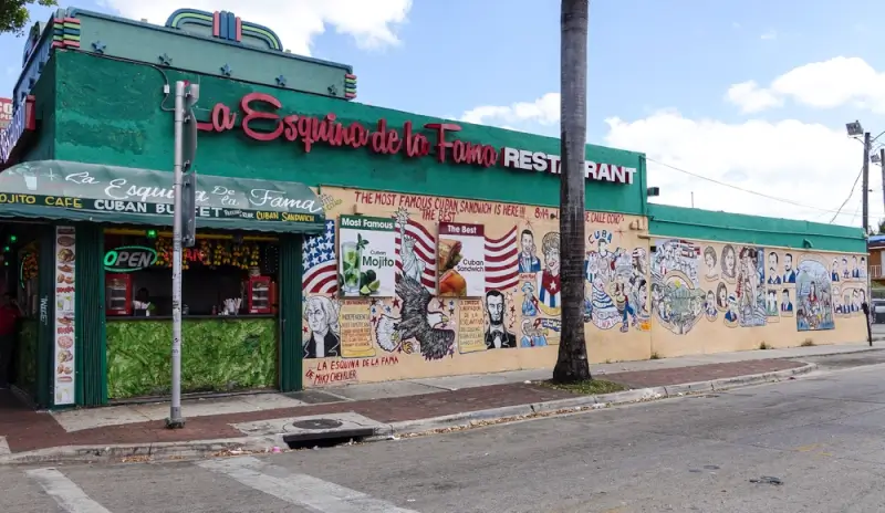 La Esquina de la Fama restaurant in Little Havana with green exterior, vintage signage, and colorful Cuban-themed murals depicting cultural icons and the American flag