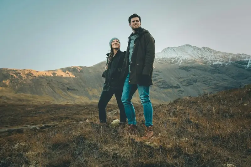 Couple hiking in Scottish Highlands with snow-capped mountains during romantic UK getaway