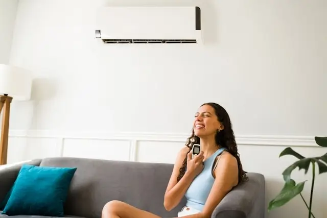 Woman smiling while adjusting room temperature with air conditioner remote control, creating optimal sleep environment in hotel room