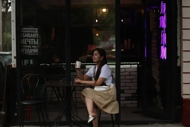 Solo female traveler enjoying quiet moment with coffee at evening cafe, embracing unhurried pace and mindful exploration
