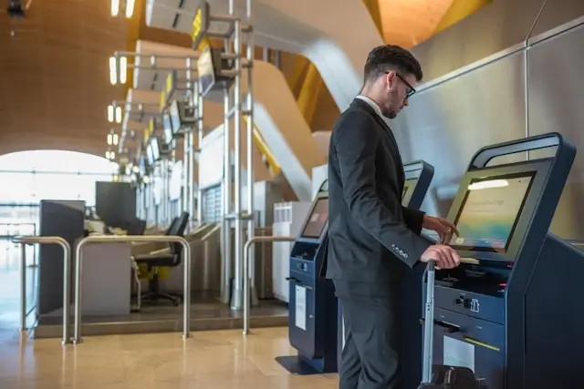 Business traveler using self-service check-in kiosk at modern airport terminal
