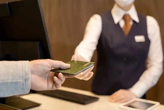 Passenger handing passport to airport service representative during check-in assistance