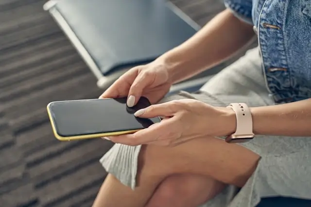 Traveler using smartphone in modern airport waiting area with comfortable seating and integrated technology for seamless connectivity