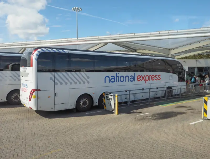 National Express coach at Stansted Airport bus station with modern terminal building in background