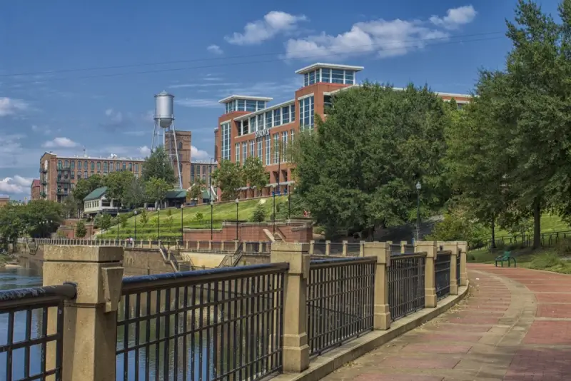 Paved Chattahoochee Riverwalk trail with metal railing showcasing things to do in Columbus, GA including waterfront views and converted mill buildings