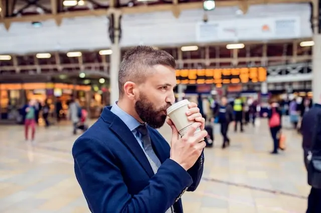 Traveler enjoying coffee in busy airport terminal during trip