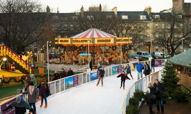 Edinburgh Christmas market with ice skating rink and vintage carousel for winter romantic getaways