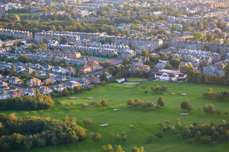 Aerial view of Edinburgh golf course surrounded by residential neighborhoods and autumn trees in Scotland