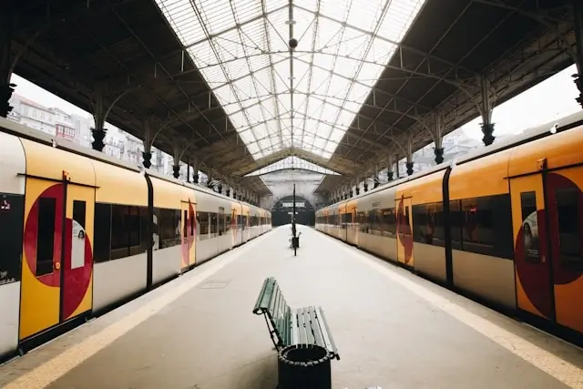 Quiet train station platform with yellow trains and glass roof during travel day