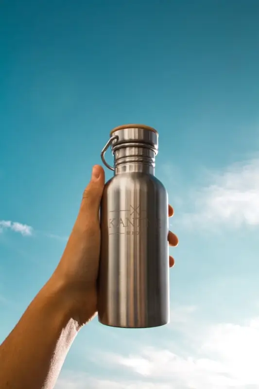 Stainless steel with engraved text water bottle held against blue sky, reusable travel bottle