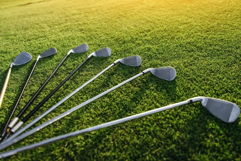 Set of golf irons arranged on manicured green grass at European golf course