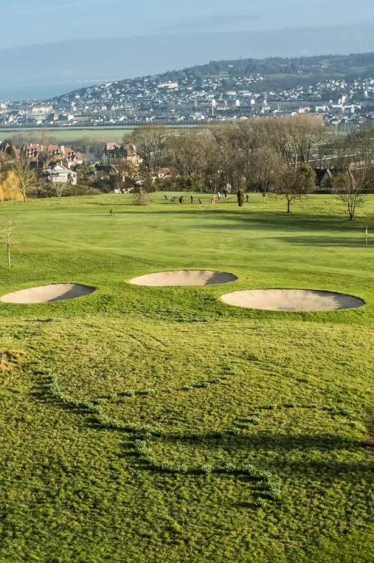 Scenic golf course in France with sand bunkers and hillside town backdrop