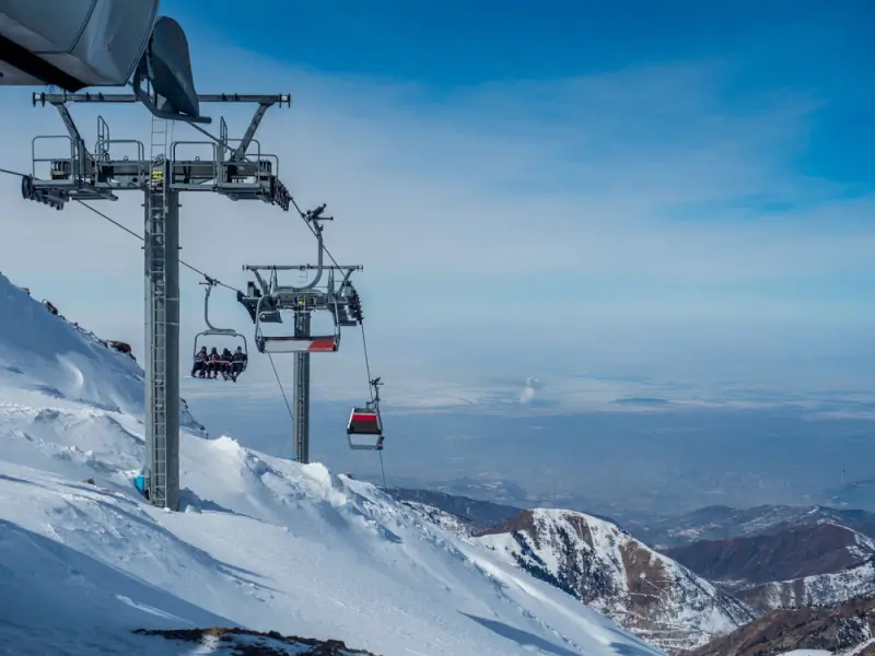Gondola lift system ascending snow-covered slopes at Shymbulak Ski Resort with Tian Shan mountain views in Almaty, Kazakhstan