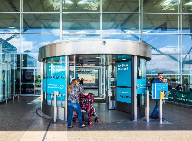Modern entrance with revolving doors at London Stansted Airport STN terminal featuring Norman Foster architecture