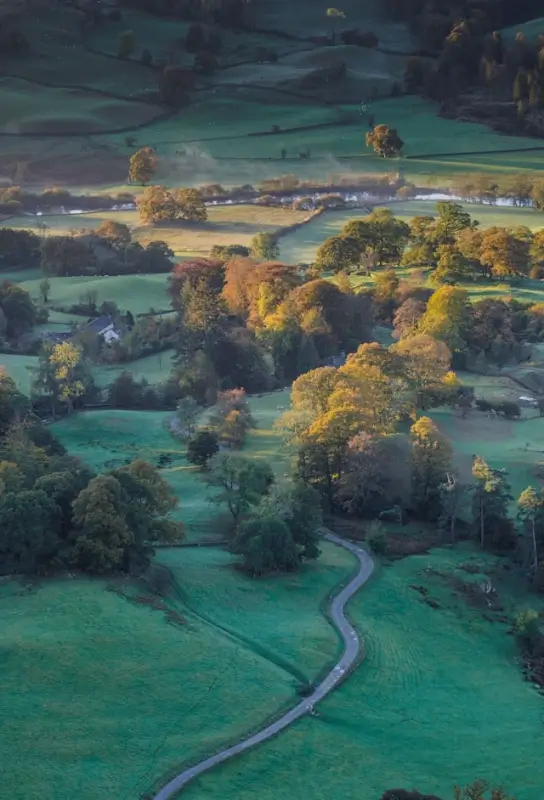 Lake District National Park rolling hills and winding road through autumn countryside in UK