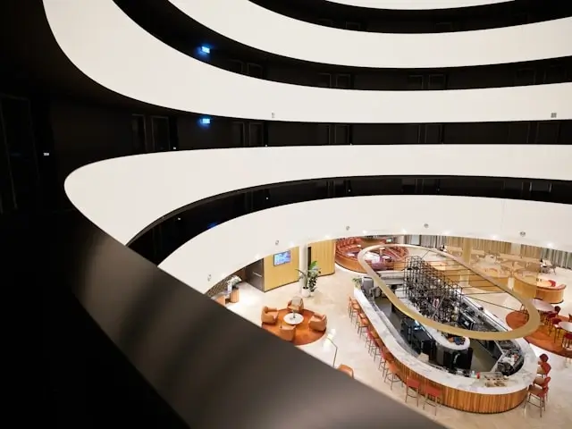 Contemporary hospitality space with dramatic curved architecture, open-plan bar area, and warm wood accents blending form with functional comfort