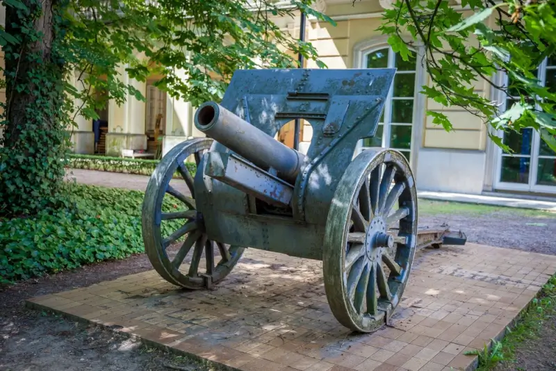 Historic artillery cannon on display outside the National Infantry Museum in Columbus Georgia with wooden wheels and weathered green paint