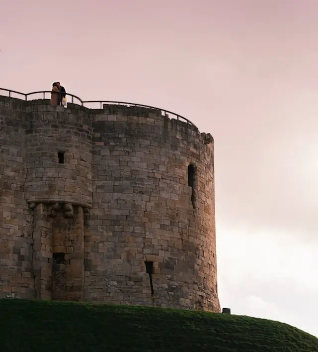 Couple kissing atop historic York Castle tower at sunset during city break