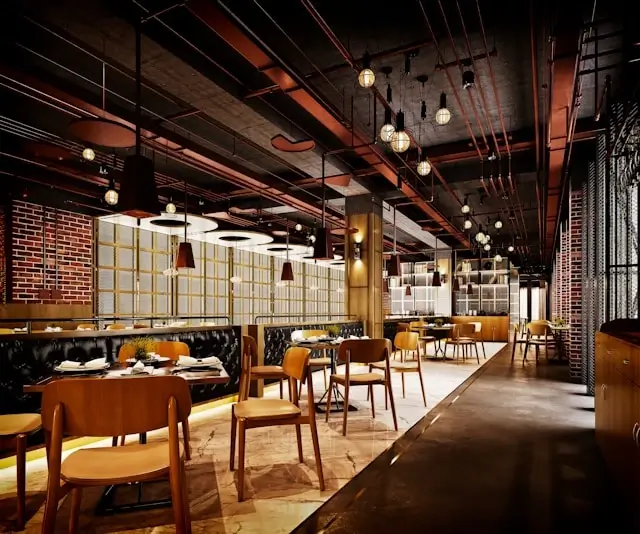 Industrial-chic restaurant interior with exposed ceiling design, ambient pendant lighting, and mixed seating arrangements creating an inviting dining atmosphere