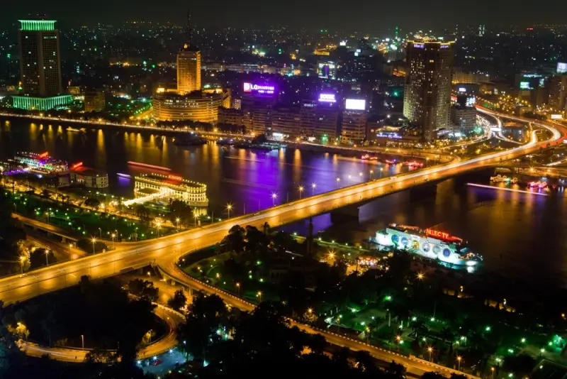 Cairo bridge spanning Nile River at night with illuminated cityscape, vibrant hotels and modern infrastructure in Egyptian capital