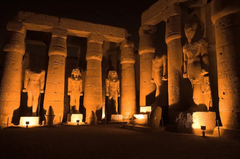 Luxor Temple illuminated at night with towering columns and pharaoh statues, prime path of totality location with longest eclipse duration
