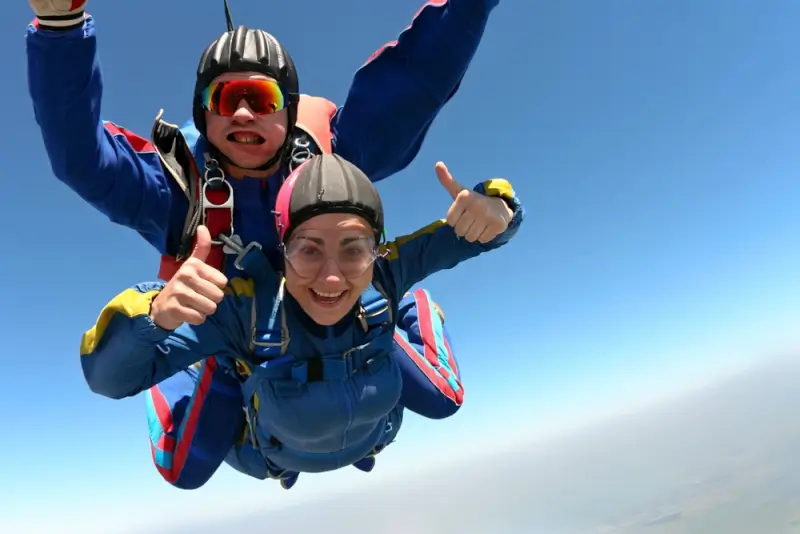 Woman experiencing tandem skydiving adventure during an active travel trip with professional instructor