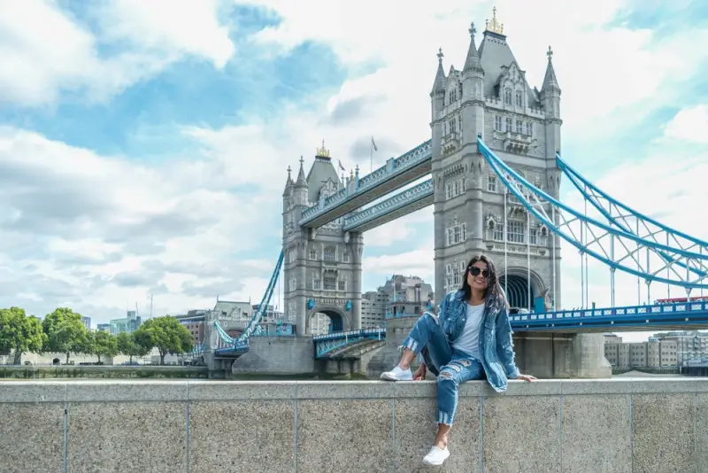 Solo female traveler posing by the River Thames waterfront with Tower Bridge in London