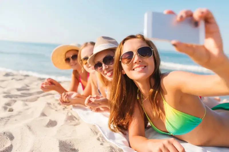 Group of women travelers taking a beach selfie together during a guided tour vacation
