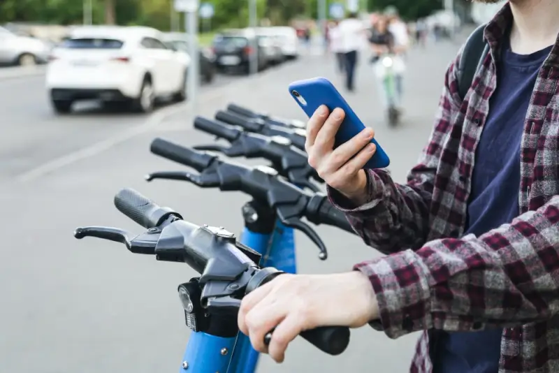 Traveler using smartphone to rent bike for affordable transportation in the city