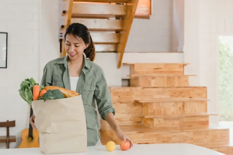 Woman preparing fresh groceries in vacation rental kitchen to save on dining costs
