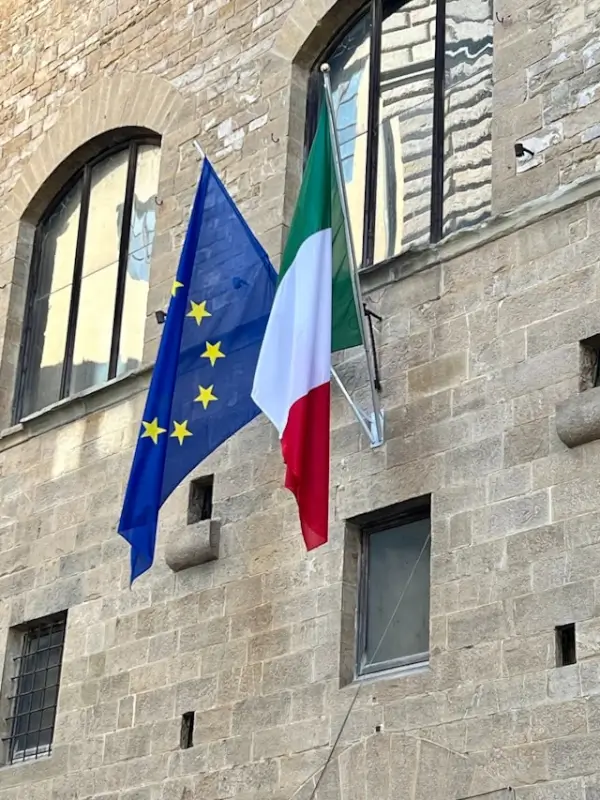 Italian and European Union flags on historic building facade for international business events