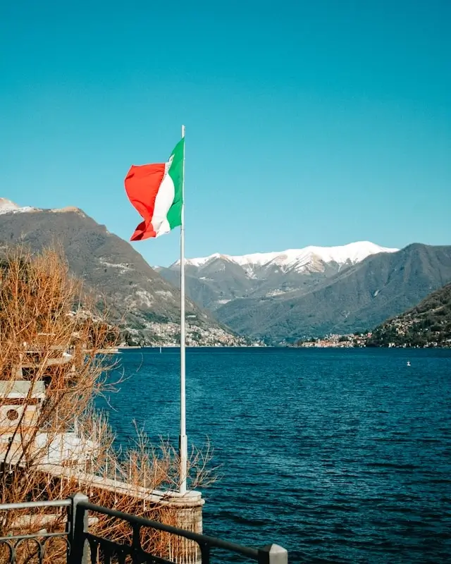 Italian flag waving over scenic mountain lake perfect for corporate retreats and executive gatherings
