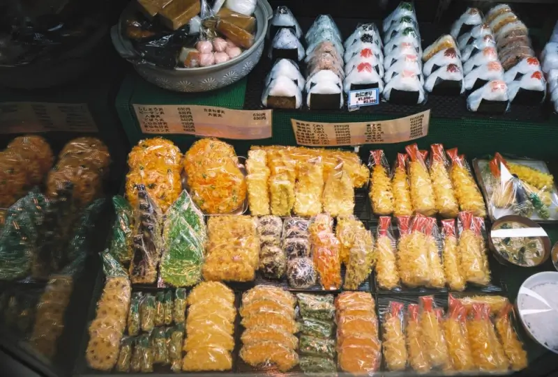Japanese street food display with onigiri and fried items as affordable local dining option